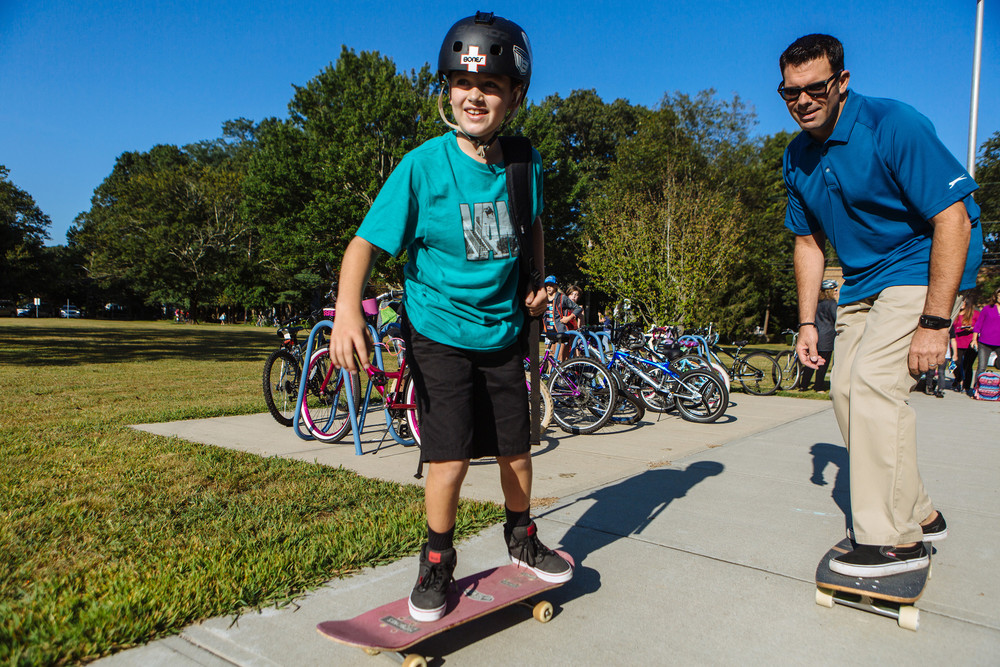 Mike Squatrito skateboards to Hampden Meadows School with his son Brian on the first day of class.