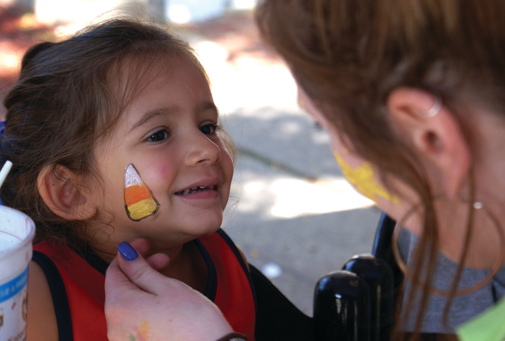 WHAT A FACE: Young Olivia Rapoza, age 3, stays still while her face was painted by volunteer Laura Philbrick at the FOOS Festival on Sunday.