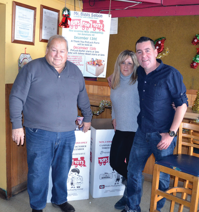 THE DRIVE IS ON: From left to right, Mr. Biggs Saloon owner Dennis Fried and bartenders Kristine Truppi and Eugene Gormley pose next to boxes they hope to fill with donations for Toys for Tots.