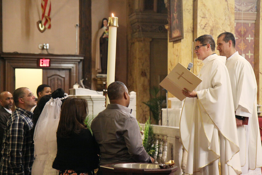 Father Jaime A. Garcia, pastor of St. Charles Borromeo Parish in Providence celebrates a recent Easter Vigil Mass, as new Catholics receive sacraments of initiation.