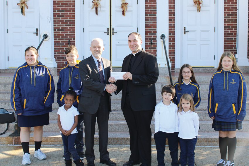 Father Ryan Simas, pastor of St. Joseph&rsquo;s Parish, presents Mayor Dan Gendron with a donation of $25,000 for the construction of a new splash park in Woonsocket, on Tuesday, Nov. 29.