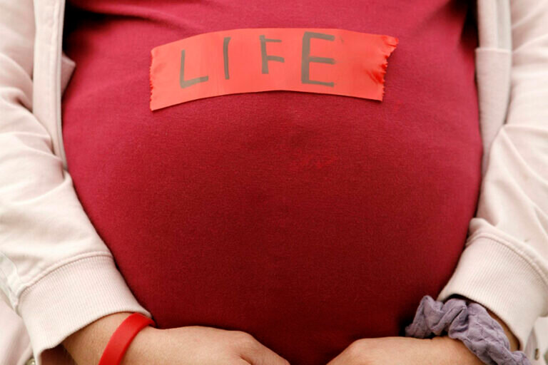 A pregnant pro-life demonstrator is pictured in a file photo outside the Supreme Court in Washington. National pro-life leaders stress the importance of the proposed &quot;Care for Her Act,&quot; which would provide support for women, specifically pregnant and parenting women. The U.S. House of Representatives in its current term has not yet taken up the bill, first introduced in 2021.