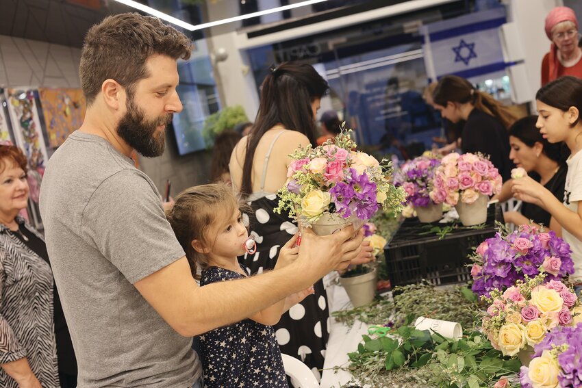 Ben Amir, a Los Angeles native who has lived in Israel since the age of 12, makes a Shabbat flowerpot with his daughter Sahar, 3, as other children and their parents also enjoy the free activity and barbecue hosted by J. Mark Interiors, adjacent to the Eldan Hotel in Jerusalem, where they stayed for two weeks free of charge thanks to the fundraising efforts of the Genesis 123 Foundation and The Isaiah Project, representing a strong collaboration between the Jewish and Christian communities.