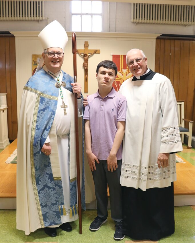 Jack Brantolino poses with Bishop Thomas J. Tobin and Father C. Roger Gagne, pastor, after receiving the sacrament of confirmation on May 11, 2019, at St. Peter Parish in Warwick. Jack, who had severe autism and passed away from a seizure last year, prepared for this day through the Autism and the Sacraments program at St. Peter Parish.