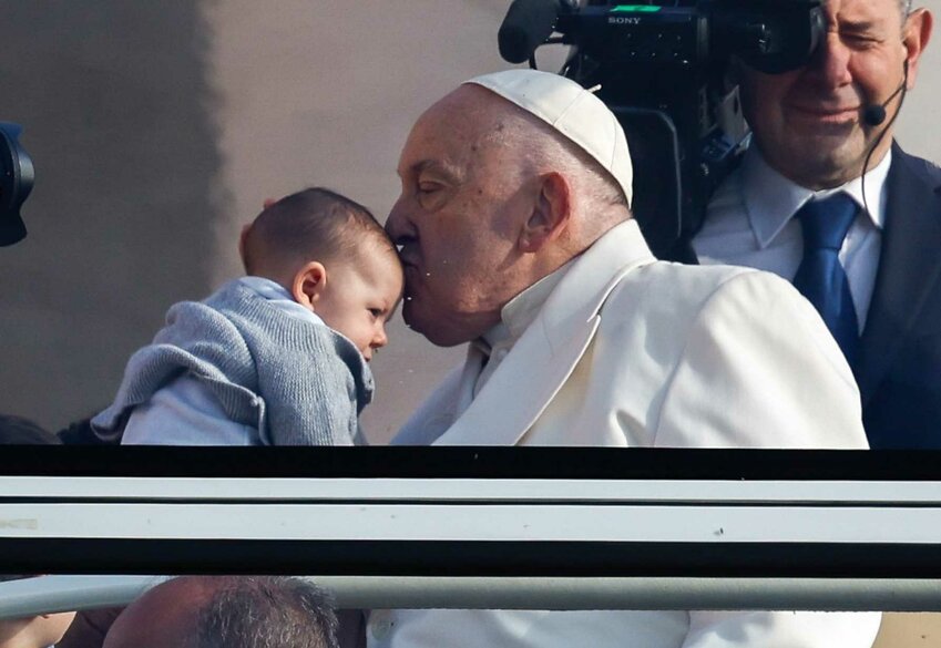 Pope Francis kisses a child as he rides the popemobile around St. Peter's Square at the Vatican before his weekly general audience April 24, 2024.