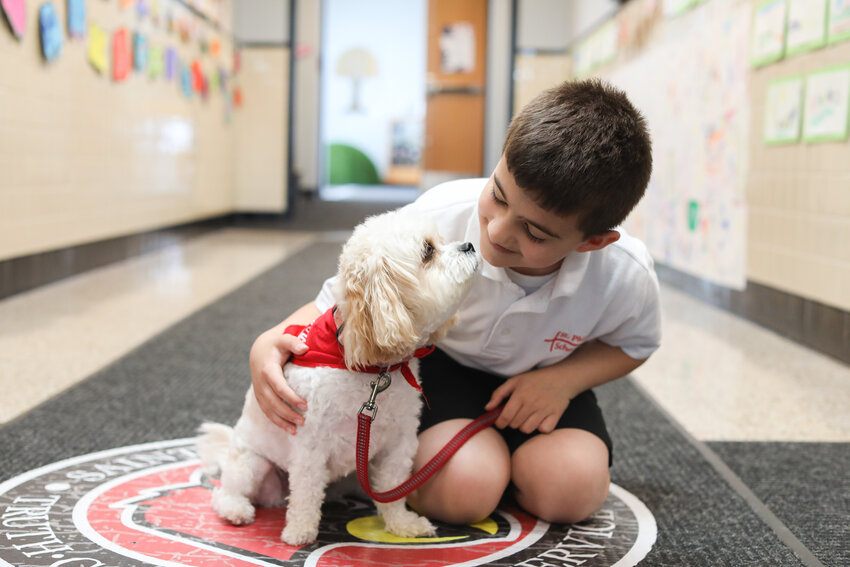 Joseph Hayek smiles with Saint Philip School therapy dog Georgi, a 3 year-old Cavachon and the star of the school’s new Cardinal C.A.R.E.S. initiative. This new program supports the well-being of students in helping them build strong foundations for academic and personal success.