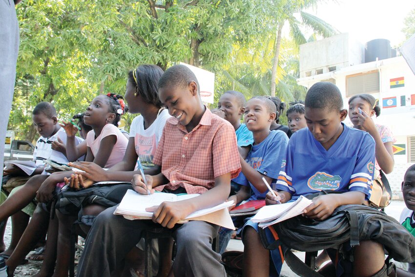 During a visit by Rhode Island Catholic in 2010, after a devastating 7.0 magnitude earthquake left 220,000 people dead, students at the secondary Catholic Louverture Cleary School in Croix-Des-Bouquets, Haiti, attend classes outside until building repairs can be made. The Haitian Project, which oversees the secondary boarding school, was founded in Providence.