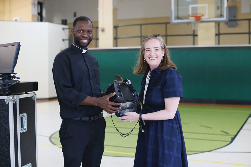 On Monday, June 17, Providence College made a donation of sound and lighting equipment that will help St. Patrick Academy, Providence, begin their first-ever theater program. Above, Erin Joy Schmidt of P.C. gifts Father Jean Joseph Brice, pastor, with lighting equipment for the school and parish.