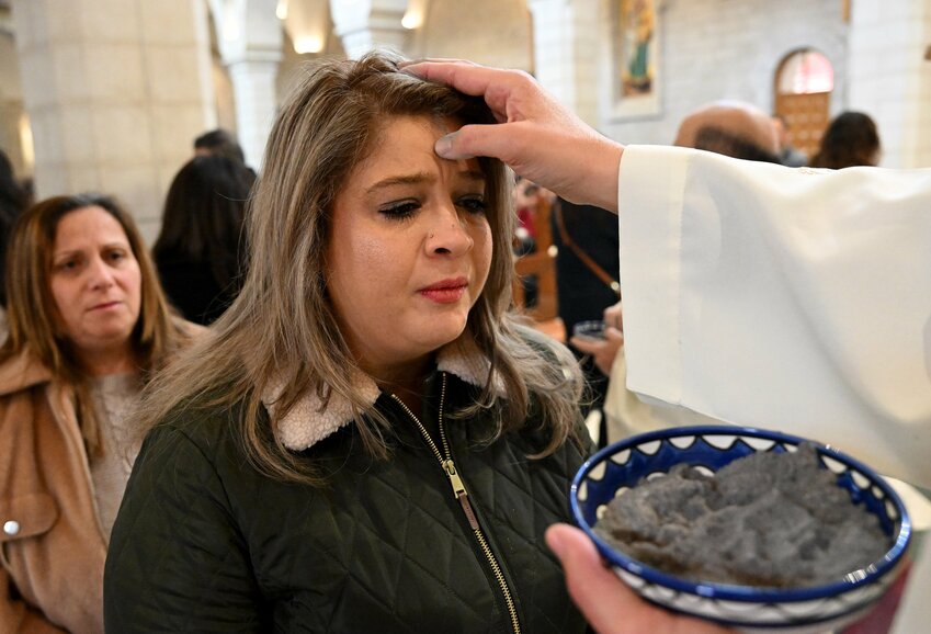 A priest places ashes on the forehead of a Palestinian woman during Ash Wednesday Mass in the Church of St. Catherine in Bethlehem, West Bank, March 5, 2025. Ash Wednesday marks the first day of Lent and the start of the six weeks of prayer and penitence before Easter.