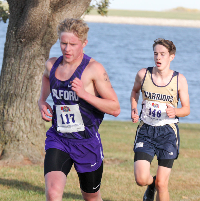 Milford's Collin Piening stays in front of a Lincoln Lutheran runner during districts Oct. 15.