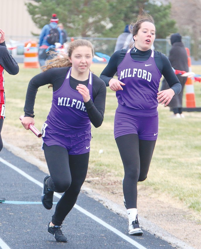 Eliza McGuire takes the baton for the final leg of the Milford 4x400-meter relay as teammate Kaitlin Kontor steps off the track April 6.