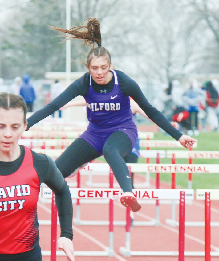 Milford's Izzy Yeackley clears the final hurdle in the 100-meter prelims at Centennial April 19.