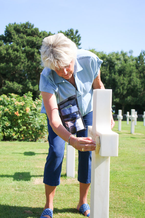 Trudy Hines sands a headstone at Normandy American Cemetery.