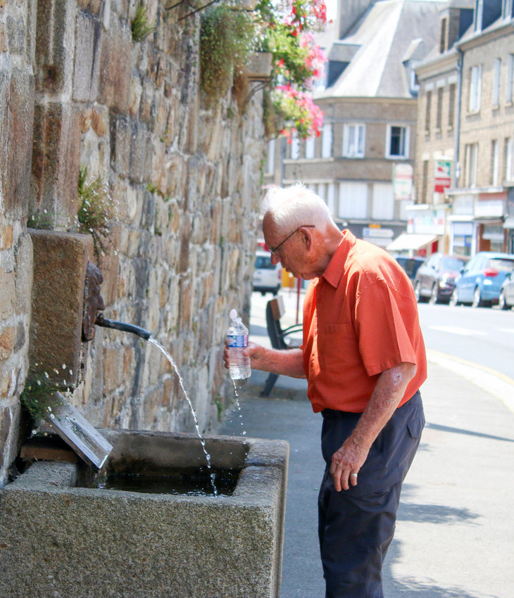 Dr. Larry Smith refills his water bottle at a spring fountain in Mortain.