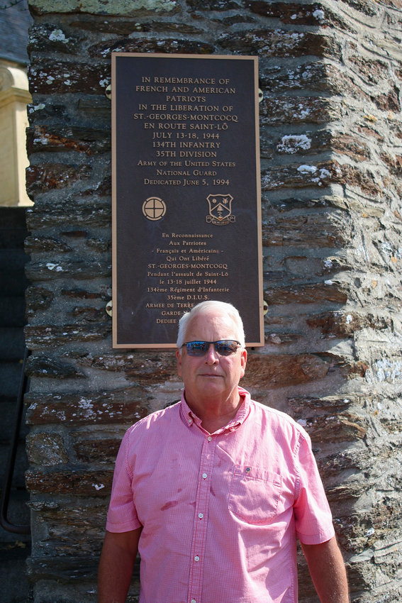 Alan Baldwin stands in front of a plaque honoring the 135th and 29th divisions.