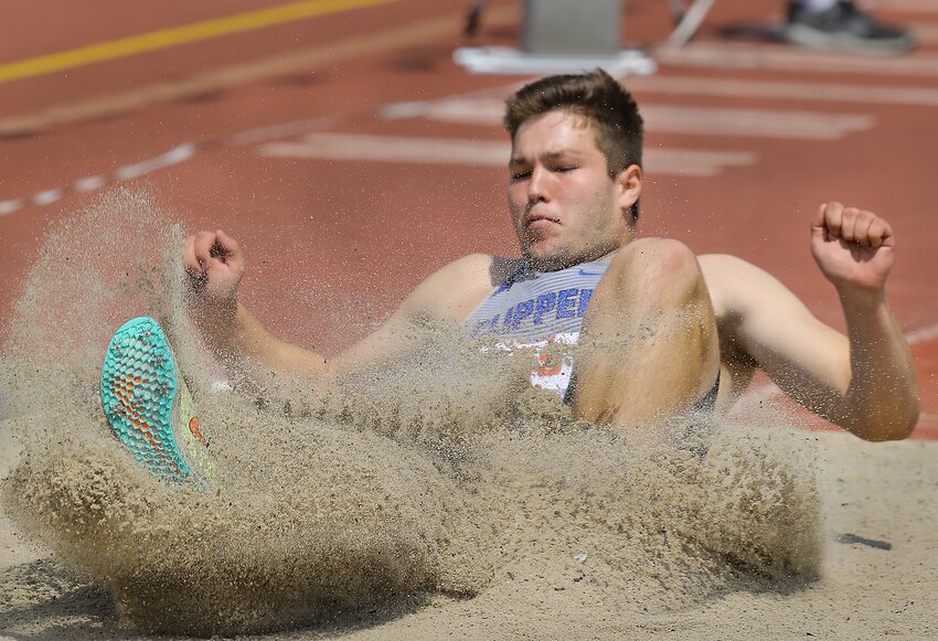 The sand explodes as Lucas Christensen of Malcolm lands in the pit druing the Class C triple jump competion. Photo by Doug Carroll.