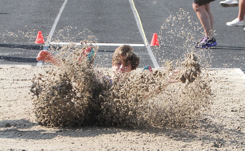 Caden Brooks of Seward kicks up sand after he lands in the long jump pit May 18.