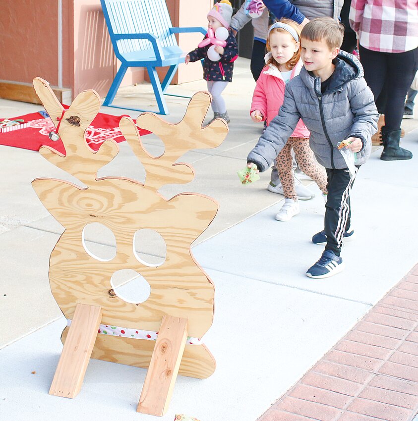 Roman, right, and Blake Daberkow of Seward, ages 6 and 3, respectively, try their hand at the beanbag toss, one of the Reindeer Games available Nov. 26.