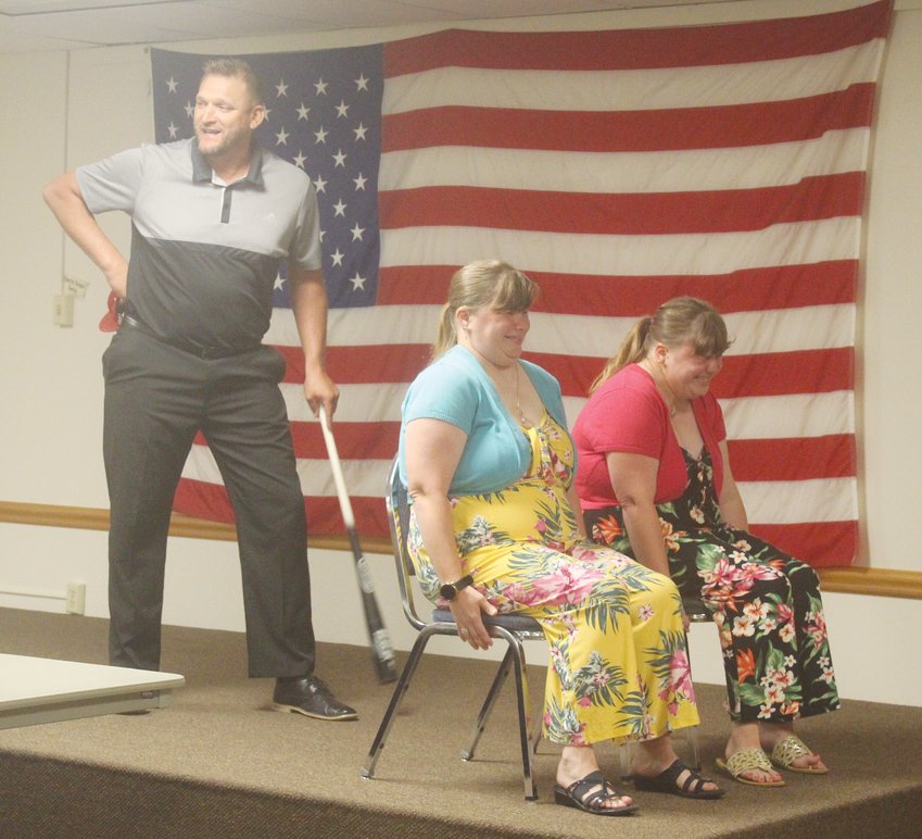 Sisters Jennifer (seated left) and Jill Schmidt wait for the sound of the bat during speaker Justin Pekarek&rsquo;s demonstration on being brave at the Seward County Special Olympics banquet Sept. 18. Pekarek swung a bat behind the women, inching closer each time so they could hear the &ldquo;swoosh&rdquo; sound. The women were brave and didn&rsquo;t flinch as the &ldquo;bat&rdquo; came within inches of their heads. Unbeknownst to them, Pekarek used a baseball cap to make the swoosh instead of a bat.