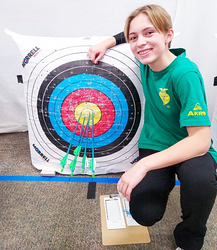Autumn Wissenburg stands with one of her two perfect 50 rounds at the Omaha Christian archery tournament Jan. 21..