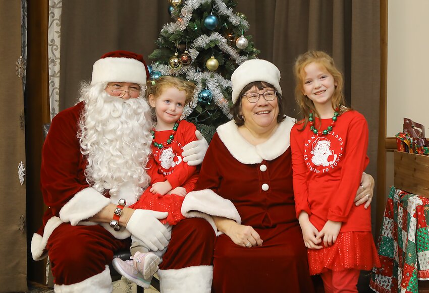 Alivia, left, and Lola Sell of Milford get their photo taken with Santa and Mrs. Claus at the Rockin' Reindeer Bash event held at the Milford Senior Center Dec. 18.