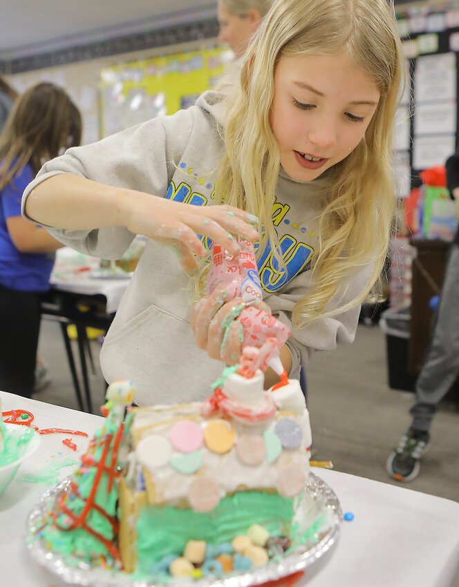Seward Elementary third grader Ava Pflieke adds colored frosting to the gingerbread house she was making at school Dec. 20.