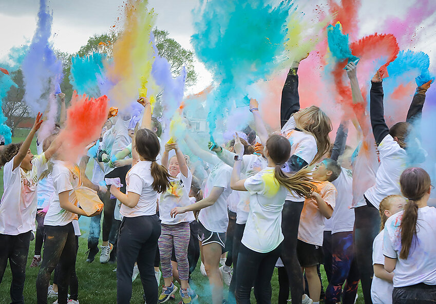 Participants in the color run held at Milford High School April 25 toss unused colored powder in the air following the event.