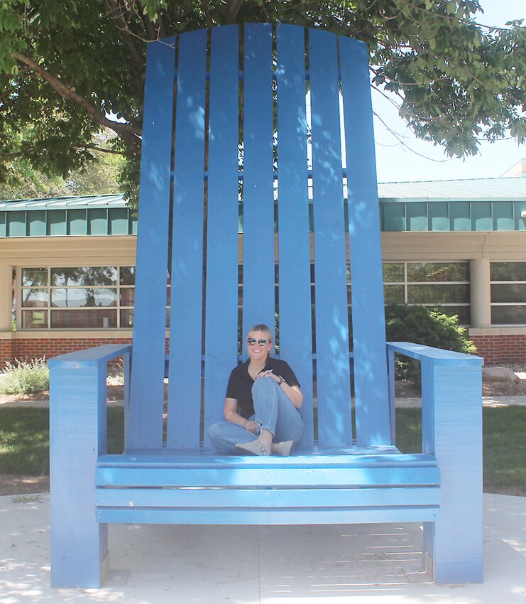 Scott Pathway director Tracy Kerner sits in the completed chair on SCC Milford's campus. The chair was a contribution to the campus by four students as a requirement of the Scott Pathway Scholarship.