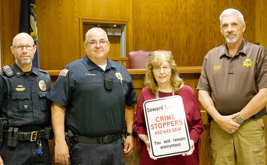 The new Crime Stoppers sign has its debut before four go up in Seward and after three went up in Milford. From left, Capt. Mike Hammond of the Seward Police Department, Chief Darrin Kremer of the Milford Police Department, Barb Liska of Seward County Crime Stoppers and Seward County Sheriff Mike Vance.