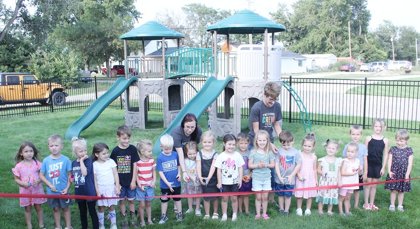 The Bellwood Montessori school in Milford celebrated its back to school night on Aug. 21, beginning its 26th year. Pictured are, back left, teacher Natasha Verwey and director/teacher Sandra Stauffer helping students all cut a ribbon recognizing installation of new playground equipment and a fence around it.