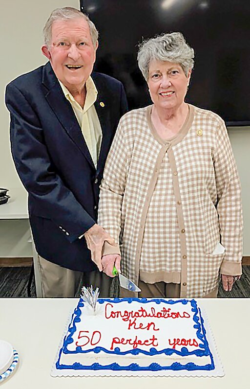 Ken and Cheryl Schmieding cut a special cake to honor Ken Schmieding’s record of 50 years’ perfect attendance.