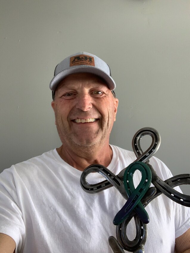 Fran Hinnenkamp holds a cross made out of antique horseshoes April 9 at his Little Birch Lake home. The cross, which was given to him after his cancer diagnosis in November 2023, is one form of support he has received.