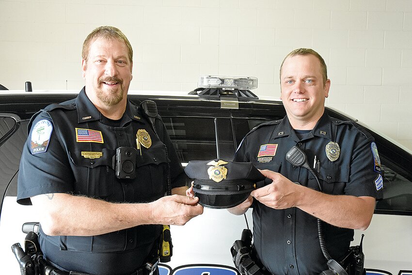 Sauk Centre Police Department Chief Bryon Friedrichs (left) passes his chief’s cap to Sgt. Joe Jensen April 18 at the SCPD garage in Sauk Centre. As Friedrichs retires, Jensen with be the new SCPD chief effective April 29.