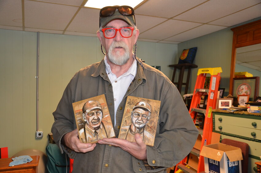 Dave Campbell holds paintings of his two brothers, Scott and Bruce, April 11 at the Foley Wellness Co-op in downtown Foley. Campbell said his brothers inspired him to open the business.