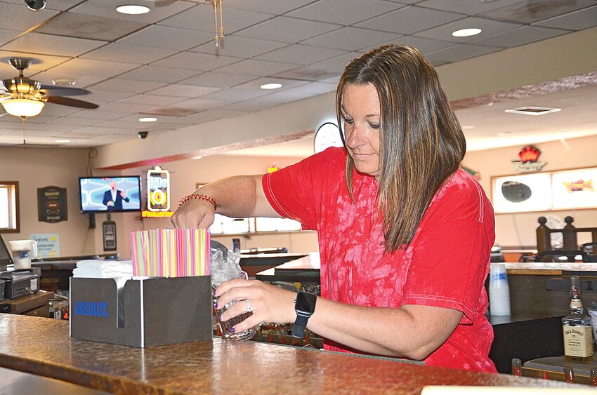 Bartender Chelsea Markfort fills a glass with ice from behind the bar at Gilman Liquor Store July 18 in Gilman. Gilman Liquor Store staff anticipate an annual rush of visitors at this years’ Gilman Days festival July 26-28