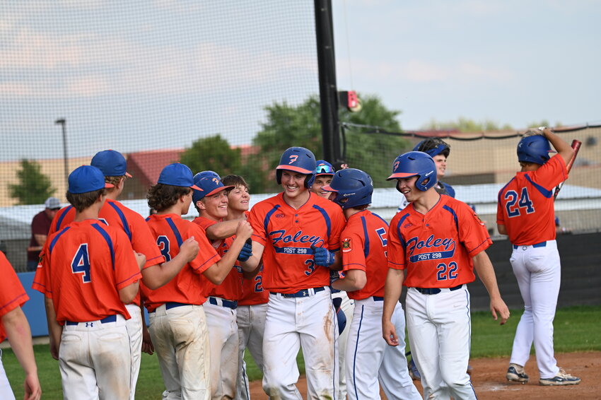 A smiling Josiah Petersen (No. 3) is mobbed at home plate by his Foley teammates after hitting a three-run home run against the St. Cloud Chutes July 16 at Foley High School in Foley. Petersen racked up an astounding seven RBIs in the 14-4 win.