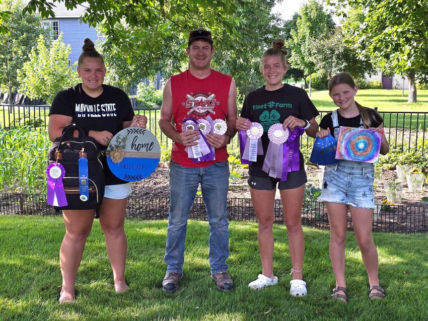 Peters siblings — Leah (from left), Tyler, Emily and Avery — hold years of county and state fair 4-H ribbons July 19 at their family’s Sauk Centre home. Avery is the youngest of the Peters bunch, looking to older Stearns County Fair champion and grand champion siblings for guidance as she prepares to show two calves this year at the Stearns County Fair July 31 through Aug. 4 in Sauk Centre.