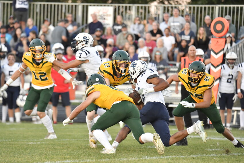 Storm sophomore linebacker Carter Pesta (23) and junior Levi Brenny (85) join forces to tackle St. Francis running back Jacob Tilly as defensive back Carter Riedeman (12) moves in Sept. 20 at the Sauk Rapids-Rice Middle School stadium in Sauk Rapids. The Storm won their homecoming game 28-14 over the Saints.