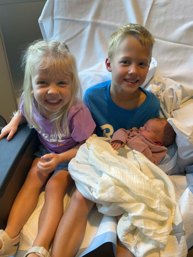 Reese Monica Kuefler is held by siblings Josie and Kyler.