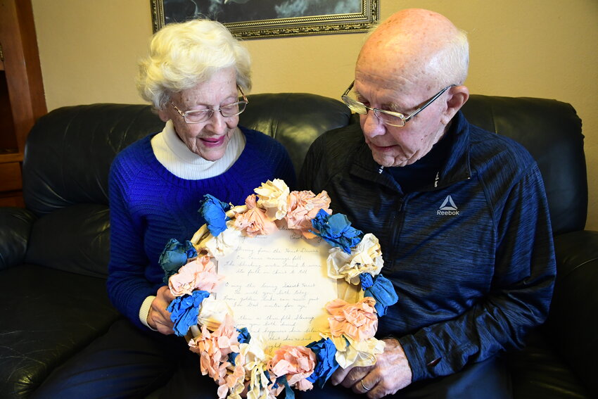 Carol and Tony Niehaus, on Oct. 3, hold the paper-mache flower wreath made by neighbors and gifted to them on their Aug. 17, 1954, wedding. The verse inside was written for them.