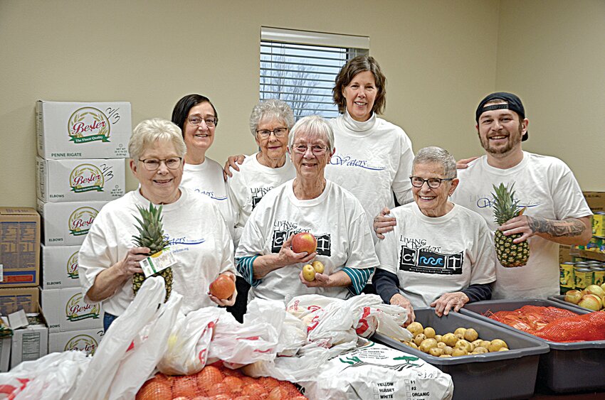 Terry Sylvester (front, from left), Judy Stene and Yvonne Crandall; (back, from left) Carol Kowalczyk, Judy Germundson, Kai Lindholm and Nick Zahurones huddle together and smile while preparing items for food shelf recipients March 4 at Living Waters Lutheran Church in Sauk Rapids. The church assists 35 to 45 families weekly.