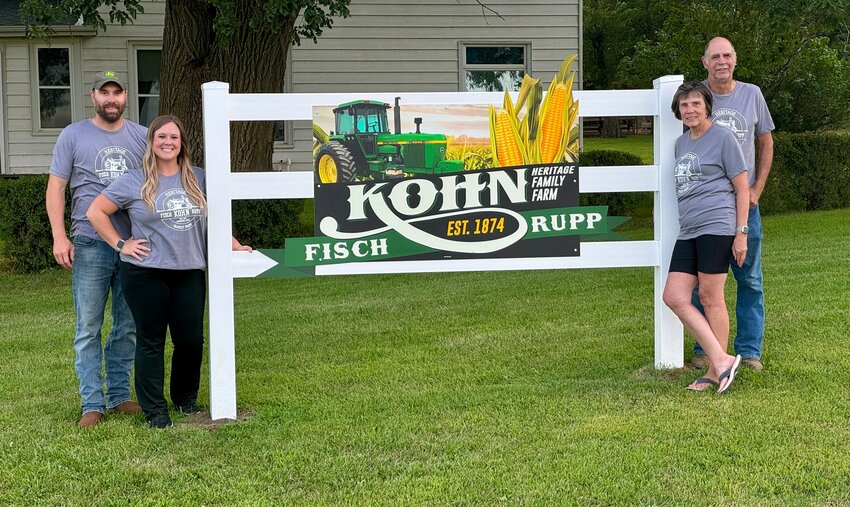 New Heritage Farm sign in front of acreage on land . On left, Kyle and Lorna Kohn. On right, Jim and Bonnie Kohn.