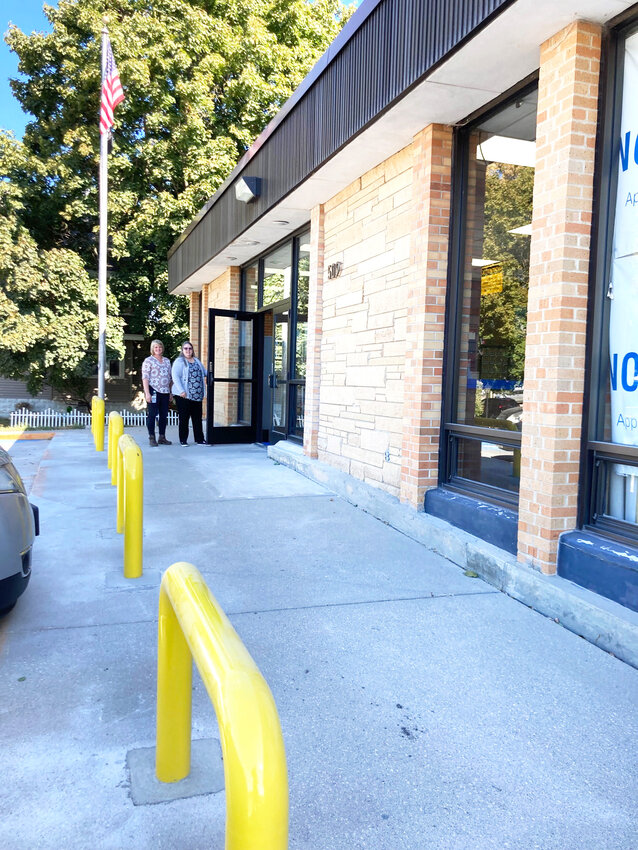 Come on in, say Supervisor Melissa Lockwood, left, and Postmaster Wanda Krier. The new yellow bollards are sunk two feet into the sidewalk.