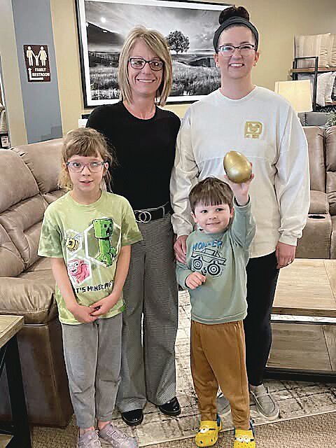 Kelli Carey, left, and golden egg winner Isabelle Wendt with her children Lily and Nico in front at Carey’s Furniture in Cherokee.