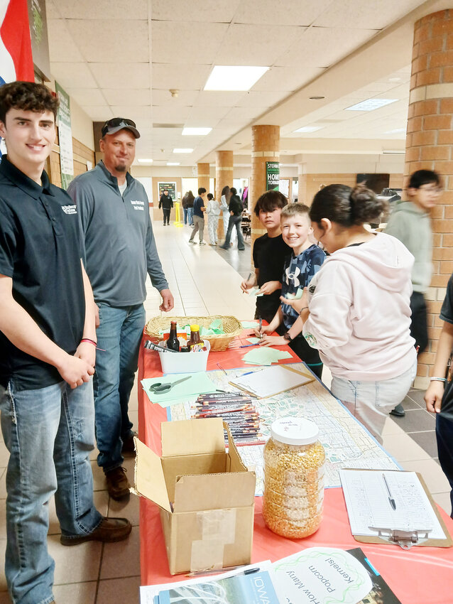Buena Vista County Pork Producers Jon Hoberman and Youth Ambassador Mason Hoberman at Storm Lake Middle School helped students guess how many popcorn kernels were in the jar at the All Iowa Meal last week.