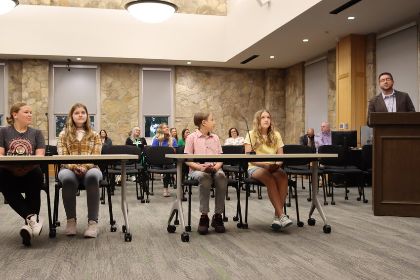Sixth graders Zoe and Willow and fifth graders Micah and Anniston spoke in front of the board of trustees with Mr. Womble on the far right.