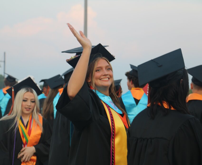 Class of 2024 graduate Aubree Adams waves to her fans in the crowd as Springtown High School's graduation ceremony on May 24 begins.