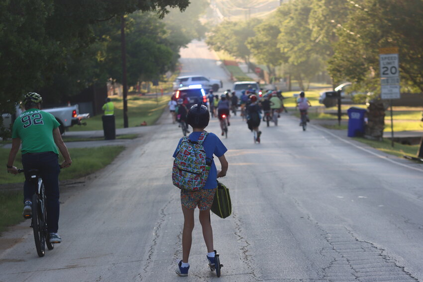 Students, teachers and city employees travel in a convoy on their way to school.