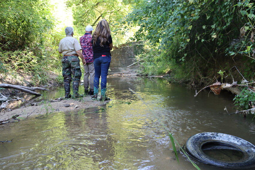 The trio looks downstream with a tire in the foreground.