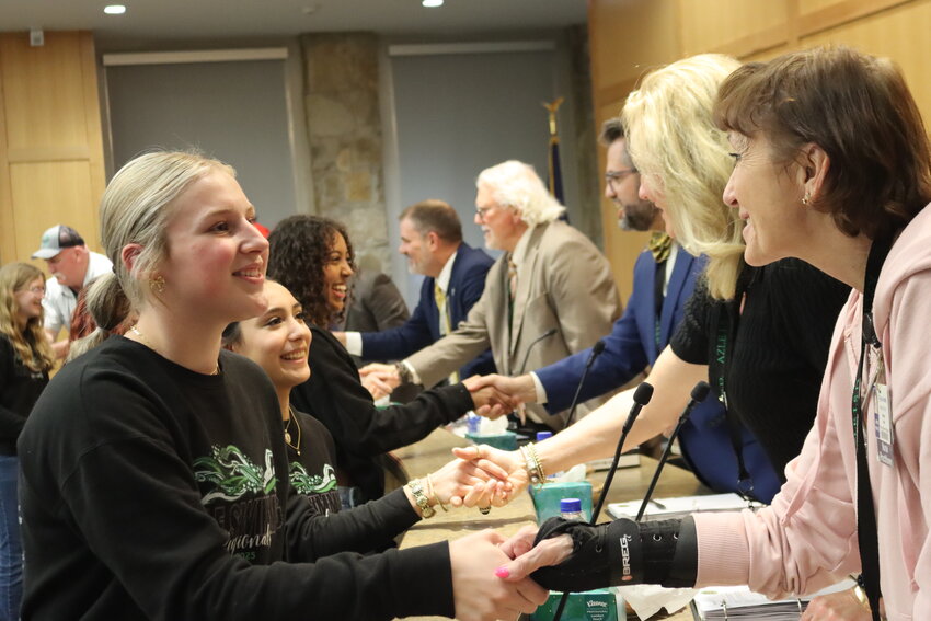 Members of Azle High School’s swim teams shake hands with trustees the night of Feb. 24.